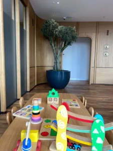 Uzm. Dr. İrem Oral kliniğinde ahşap masa üzerindeki çocuk oyun köşesi – stacking halka, puzzle ve oyuncak ev